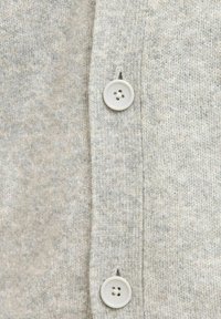 Lysegrå strikket cardigan med en tekstureret overflade, en enkelt række hvide knapper med fire huller, og en afslappet pasform.