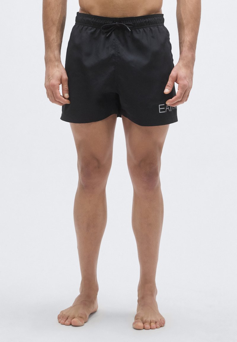 Fekete fürdőnadrág rugalmas derékpánttal és húzózsinórral. Bal lábszáron kis logóval, könnyű, texturált anyagból készült.