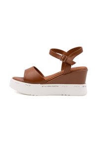 Bruine leren wedge sandalen met een brede band aan de voorkant en een verstelbare enkelriem. Heeft een witte platformzool met merkaanduiding.