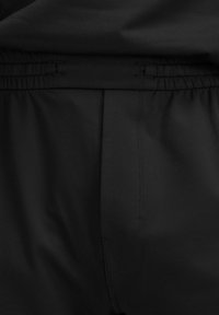 Zwarte joggers van zacht materiaal, met een elastische tailleband, zijzakken en een gladde textuur. Eenvoudig en functioneel ontwerp.
