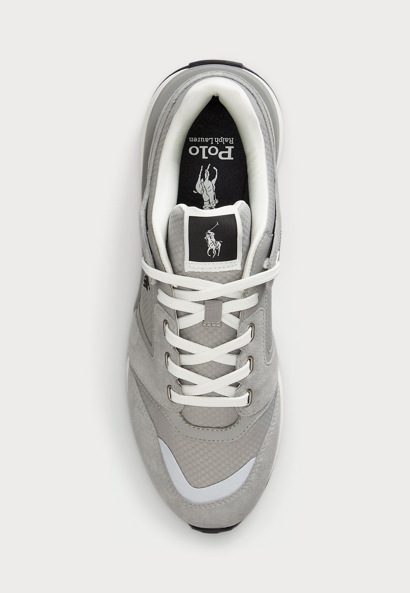 Graue und weiße Polo Ralph Lauren Sneaker mit weißen Schnürsenkeln, gepolstertem Kragen und Polo-Logo auf der Zunge und der Innensohle, Draufsicht auf weißem Hintergrund.