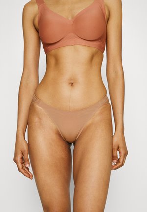 Light brown seamless bra and matching thong in a soft, smooth fabric, featuring wide straps and minimalistic design for comfort.