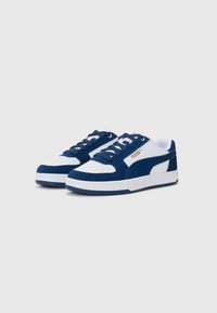 Navy and white low-top sneakers featuring suede and leather materials, round toe, flat laces, and a gold logo accent on the side.