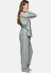 Ensemble de pyjama à carreaux dans des tons de gris et de bleu ; haut à manches longues et pantalon ample avec une texture douce et des fentes latérales pour le confort.