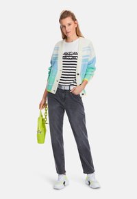 Knit cardigan with pastel blue, green, and cream stripes, layered over a black and white striped T-shirt. Grey denim jeans and white sneakers.