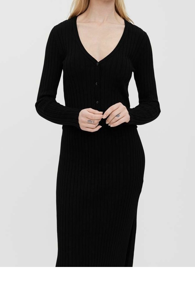 Mustan ribattua neulemekko, jossa on pitkät hihat, V-pääntie ja napit edessä. Tyylissä on kapea muotoilu ja sivuhalkio, joka helpottaa liikkuvuutta.