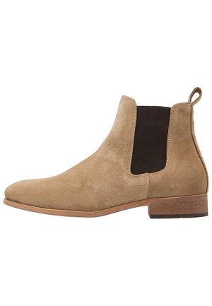 Botte Chelsea en daim couleur noisette avec panneaux élastiques latéraux noirs, languette de traction au talon, petit talon en bois empilé, et embout en amande.