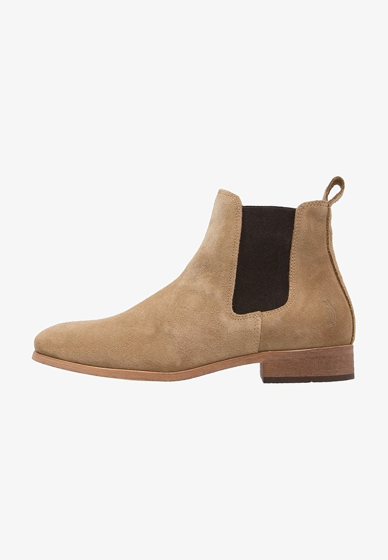 Botte Chelsea en daim couleur noisette avec panneaux élastiques latéraux noirs, languette de traction au talon, petit talon en bois empilé, et embout en amande.