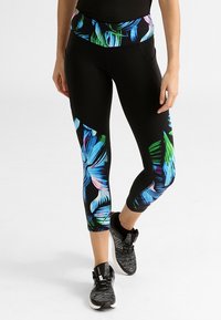 Leggings noirs avec un motif de feuilles tropicales vibrant en bleu, vert et rose. Présente une taille haute et un design ajusté.