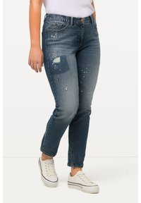Džínové kalhoty s středně modr ým omakem, s nášivkou na levém stehně, s opotřebovanými detaily a akcenty sprejové barvy. Elastický pas.
