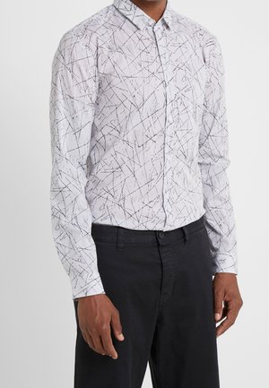White button-up shirt with a black geometric pattern, long sleeves, and a standard collar. Worn with dark trousers.