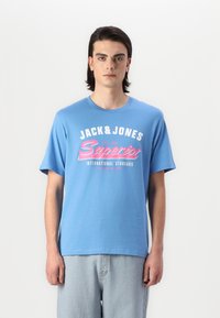Mėlynas medvilninis marškinėliai, ant kurių yra baltas ir rožinis užrašas "JACK & JONES Superior". Trumpomis rankovėmis ir apvalia iškirpte. Kasdienis stilius.