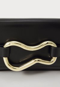 Musta nahkainen käsilaukku, jossa on kulta-muotoinen metallilukko aaltoilevalla kuvioinnilla ja teksturoidulla pinnalla, jota täydentävät mustat metallikoristeet.