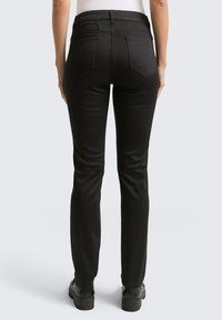 Zwarte skinny jeans met een gladde textuur, hoge taille en vier zakken. Heeft discrete stiknaden en een slim-fit snit langs de benen.