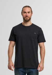 Czarnoszary t-shirt z krótkim rękawem wykonany z bawełny. Okrągły dekolt z lewej strony piersiowy kieszonką z małym pomarańczowym i białym akcentem.