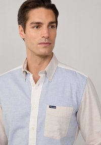 Lichtblauwe en beige button-up overhemd met contrasterende mouwen, borstzak en merklabel. Zachte textuur met een kraagdesign.