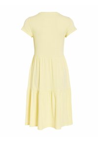 Aizmugures skats uz īsām piedurknēm, gaiši dzeltenu, vairāklīmeņu midi kleitu ar piegulošu korseti un savāktu svārku.