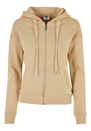 Bež dukserica sa zipom, s kapuljačom na vezanje, rebrastim rukavima i donjim rubom, te prednjim džepom. Sadrži srebrni zip i mali logotip na donjem rubu.