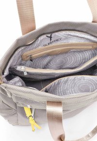 Sac à main tissé gris avec un extérieur texturé, un intérieur beige, plusieurs compartiments, des poches zippées et une étiquette d'accent jaune.