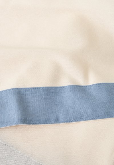 Κοντινό ενός μπεζ υφάσματος με μια φαρδιά οριζόντια ανοιχτό μπλε λωρίδα και ορατή ραφή και υφή.