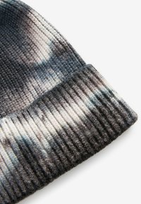 Strickmütze mit einem Farbverlaufsmuster aus dunkelgrau, hellgrau und creme, mit gerippter Textur und umgeschlagenem Saum.
