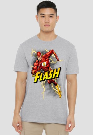 Young man wearing light gray T-shirt with a graphic of The Flash running, surrounded by yellow lightning and bold text "The Flash."
