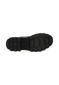 Suola di scarpa sportiva nera con una superficie in gomma testurizzata, dotata di scanalature profonde e di un design angolare per una migliore aderenza e stabilità.