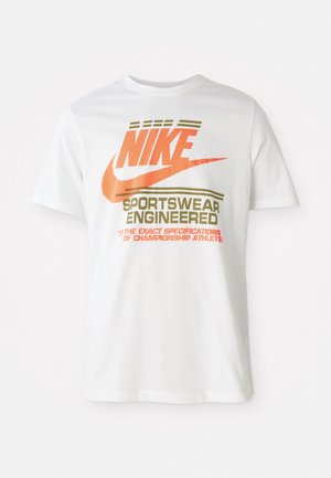Valge puuvillane T-särk, millel on suur oranž "NIKE" logo ja roheline tekst "SPORTSWEAR ENGINEERED" koos täiendavate spetsifikatsioonidega.