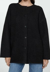 Czarny kardigan z wełny z domieszką z okrągłym dekoltem, sześcioma guzikami z przodu i dwoma przednimi kieszeniami. Posiada luźne rękawy i teksturowane wykończenie.