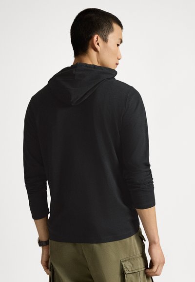 Svart långärmad hoodie med avslappnad passform och fastsydd huva, kombinerad med olivgröna cargobyxor som visar upp ett texturerat tyg.