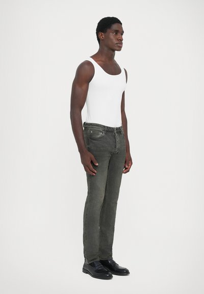 Gray denim jeans with a slim-fit cut, front pockets, and dark stitching details, paired with a white tank top and black shoes.