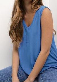 Top azzurro senza maniche con scollo a V, tessuto testurizzato e vestibilità ampia, abbinato a jeans in denim blu casual.