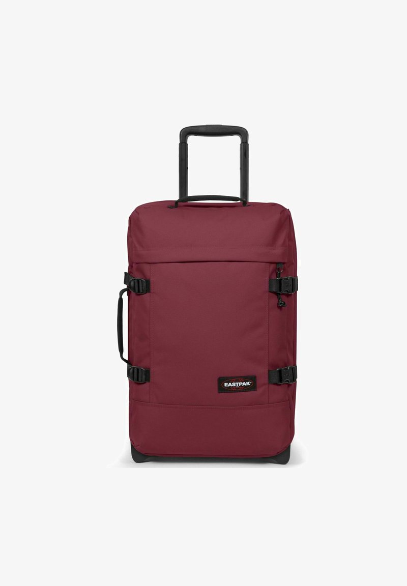 Valigia rossa con ruote, dotata di manico estraibile, cinghie regolabili, superficie liscia, tessuto resistente e una toppa nera con logo sul davanti.