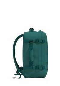 Zaino turchese con una forma rettangolare, realizzato in materiale resistente. Presenta spallacci regolabili, una maniglia e fibbie sicure. Texture liscia.