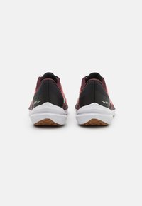 Scarpe sportive rosse e nere con una tomaia testurizzata, una suola bianca ammortizzata e una suola esterna marrone, caratterizzate da un design elegante e una struttura di supporto.