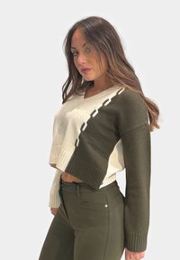 Maglione corto con design diviso in beige e verde oliva, con polsini a coste. Texture liscia e dettaglio a blocchi di colore a contrasto.