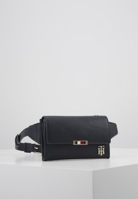 Černá křížová taška z jemné kůže s klopou, zlatými kovovými detaily a pruhovaným dekorativním panelem. Nastavitelný popruh a reliéfní logo.