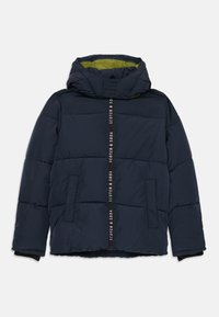 Doudoune bleu marine avec capuche, fermeture éclair avant avec l'inscription "SCOTCH & SODA", poches latérales et doublure verte à l'intérieur de la capuche.