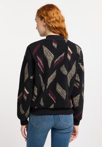 Zwarte bomberjack met textuur, voorzien van een patroon van abstracte vormen in beige, rood en groen; ribgebreide manchetten en tailleband.