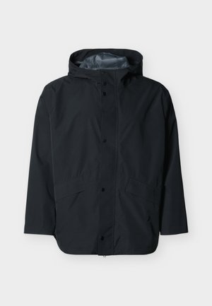 Musta vedenpitävä hupullinen takki, jossa on etuosassa nepparikiinnitys ja kaksi viistosti sijoitettua taskua, asetettuna tasaiselle valkoiselle taustalle.