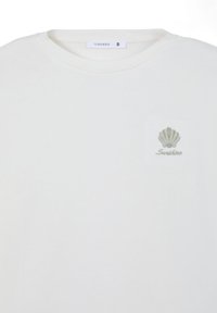 T-shirt bianco in cotone con un piccolo ricamo a forma di conchiglia verde e la scritta "Sunshine" sottostante. Collo a giro e maniche corte.