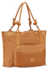 Torba tote z beżowej tkaniny z fakturowaną przednią kieszenią, węzłowymi uchwytami i detalem logo na pasku. Posiada gładkie wykończenie i wzmocnioną konstrukcję.