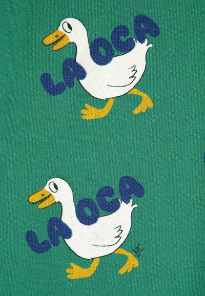 Green fabric featuring a white cartoon duck with an orange beak and yellow feet. Text "LA OCA" in bold blue letters beside the duck.