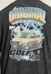 T-shirt noir avec un graphisme d'une voiture Volkswagen Golf MK1 jaune, éclairs et texte « The Original 74 Golf MK1 Designed for speed since 1974. »