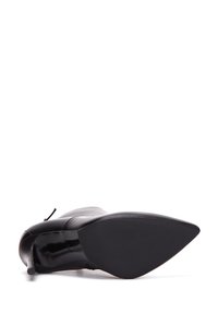 Bota negra de tacón alto con punta afilada, parte superior de cuero elegante y un acabado mate suave en la suela. Acentuada con un tacón delgado.