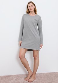 Szara, długosleeve nocna sukienka z okrągłym dekoltem, kieszonką na piersi z delikatnym nadrukiem i lekko zaokrąglonym dołem. Miękka faktura materiału.