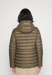 Olivově zelená péřová bunda s kapucí, která má prošívaný design a hladkou texturu. Rukávy jsou přiléhavé a lem je mírně zakřivený.