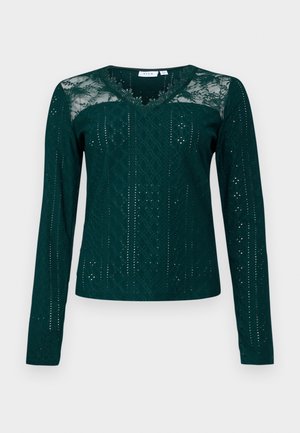 Haut à manches longues teal avec un décolleté en V, des panneaux en dentelle et des motifs découpés complexes. Tissu doux avec des variations de texture.