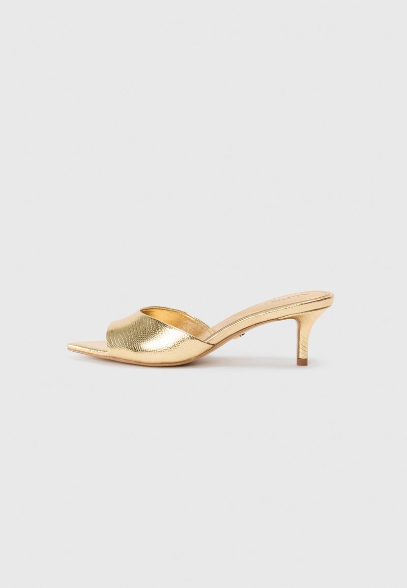 Gold heeled mules with a textured pattern, open toe, and a slender mid-heel. Smooth finish and curved silhouette.