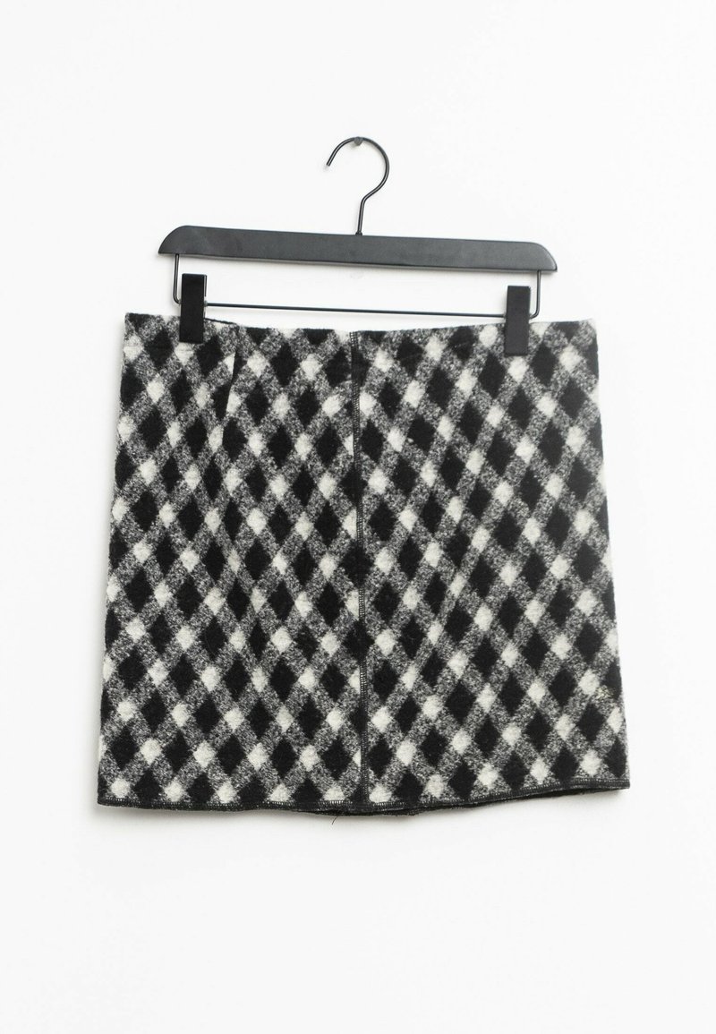 Falda mini de cuadros en blanco y negro con material de lana texturizada, que presenta un patrón de diamantes y un dobladillo recto. Colgada de una percha negra.